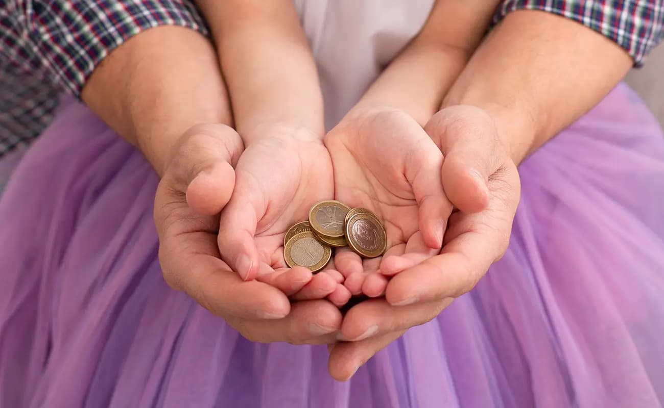 An adult's hands and a child's hands holding a few coins