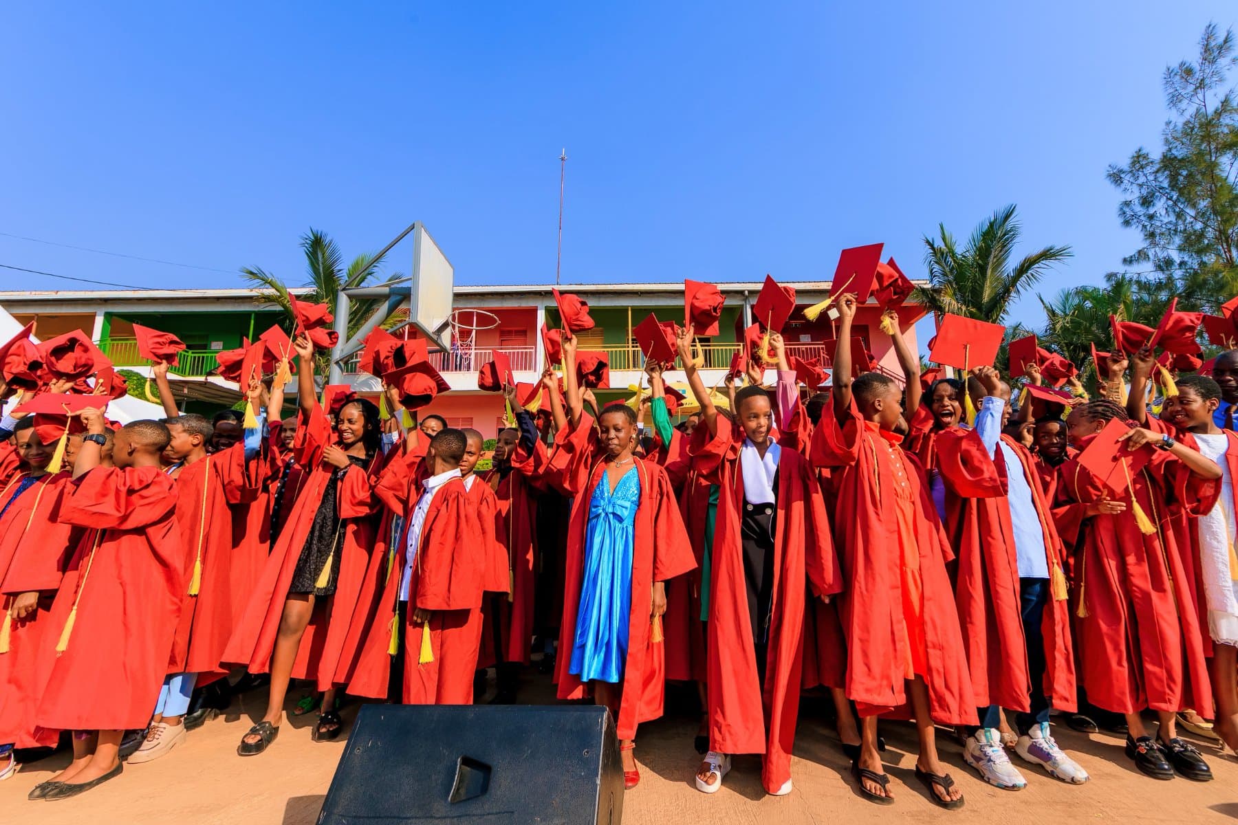 Pupils in red graduation gowns and caps gathered together