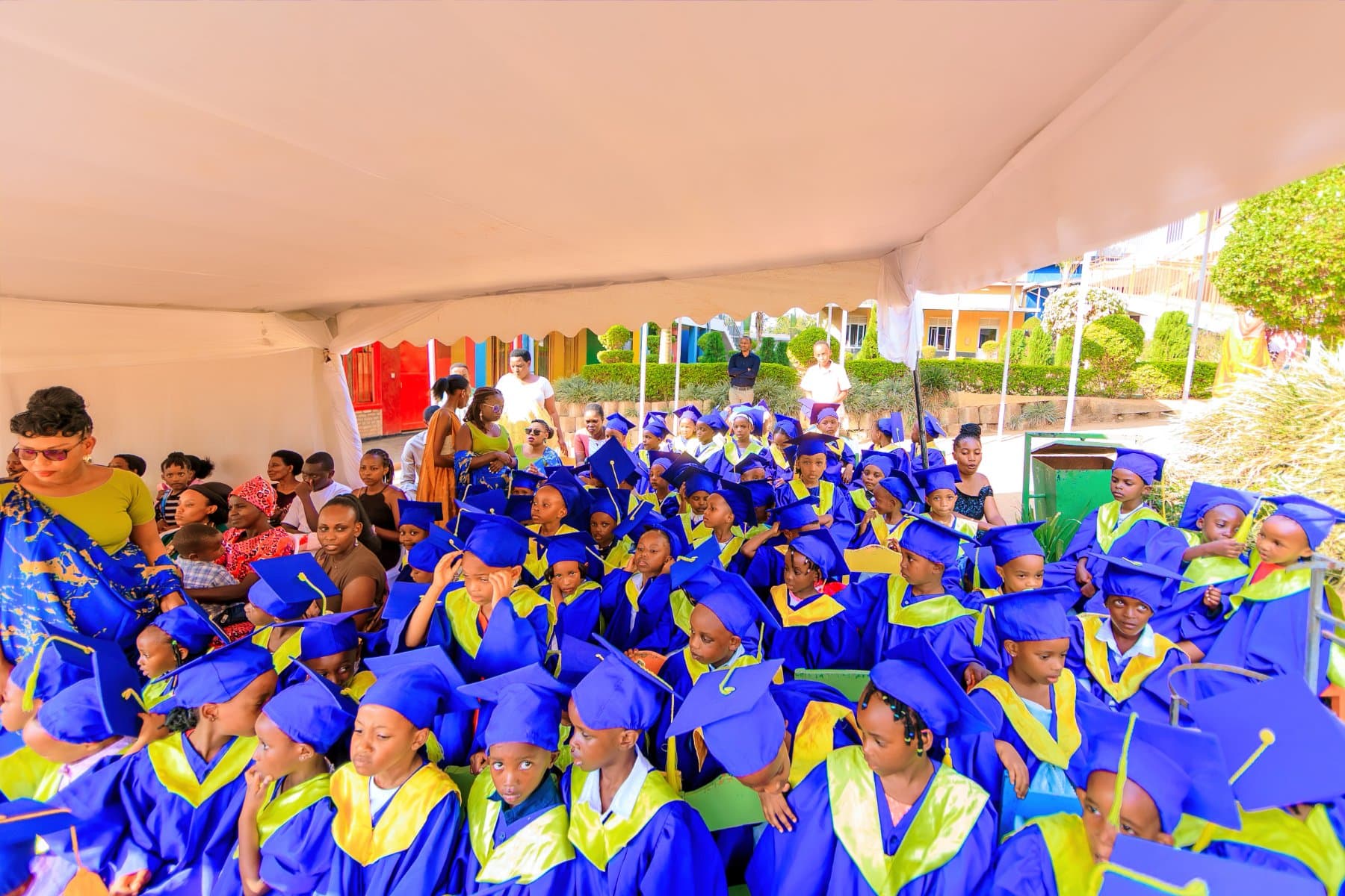 A large group of pupils in blue graduation gowns seated together