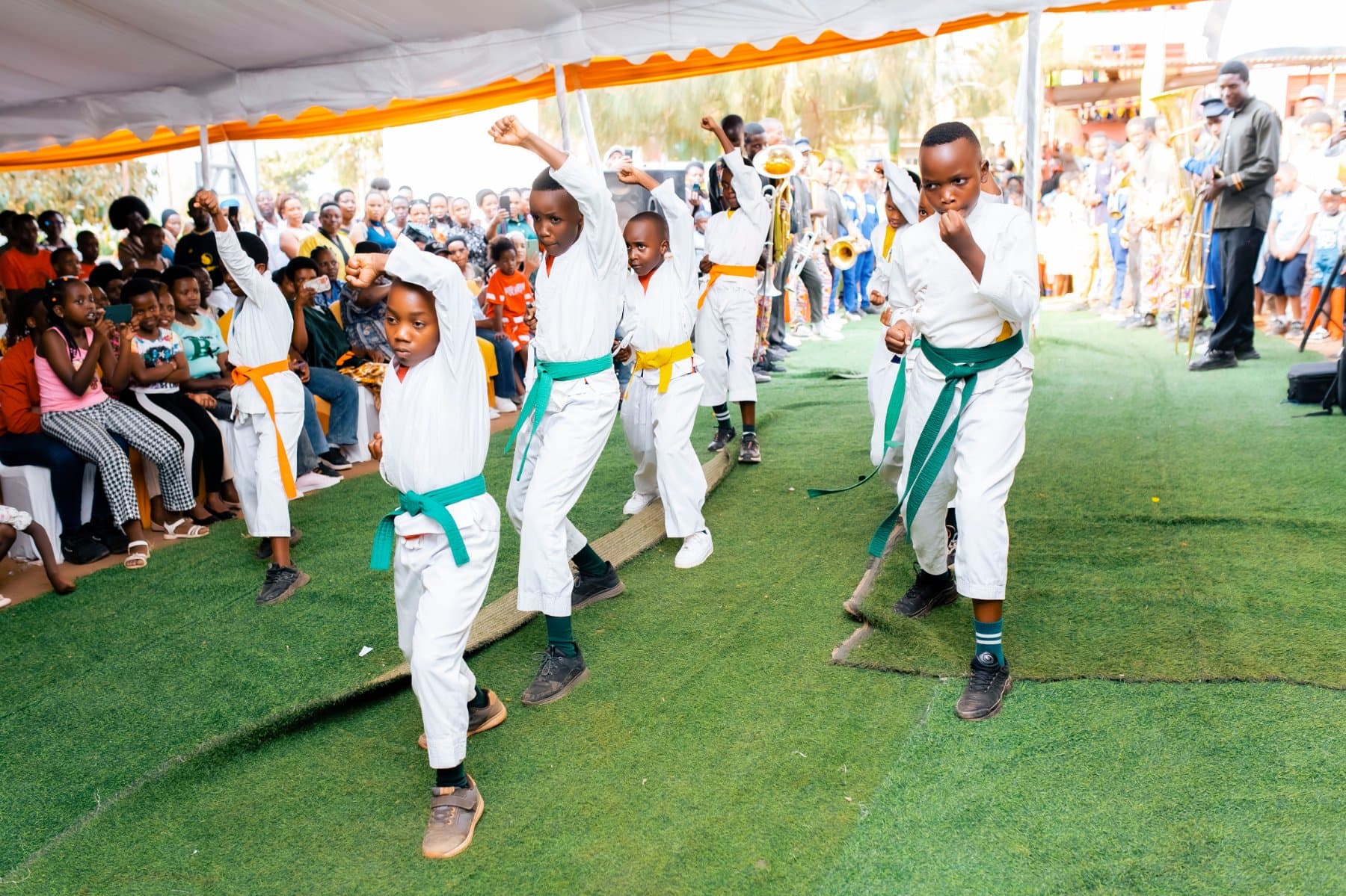 Pupils in white karate uniforms with coloured belts, mid-demonstration