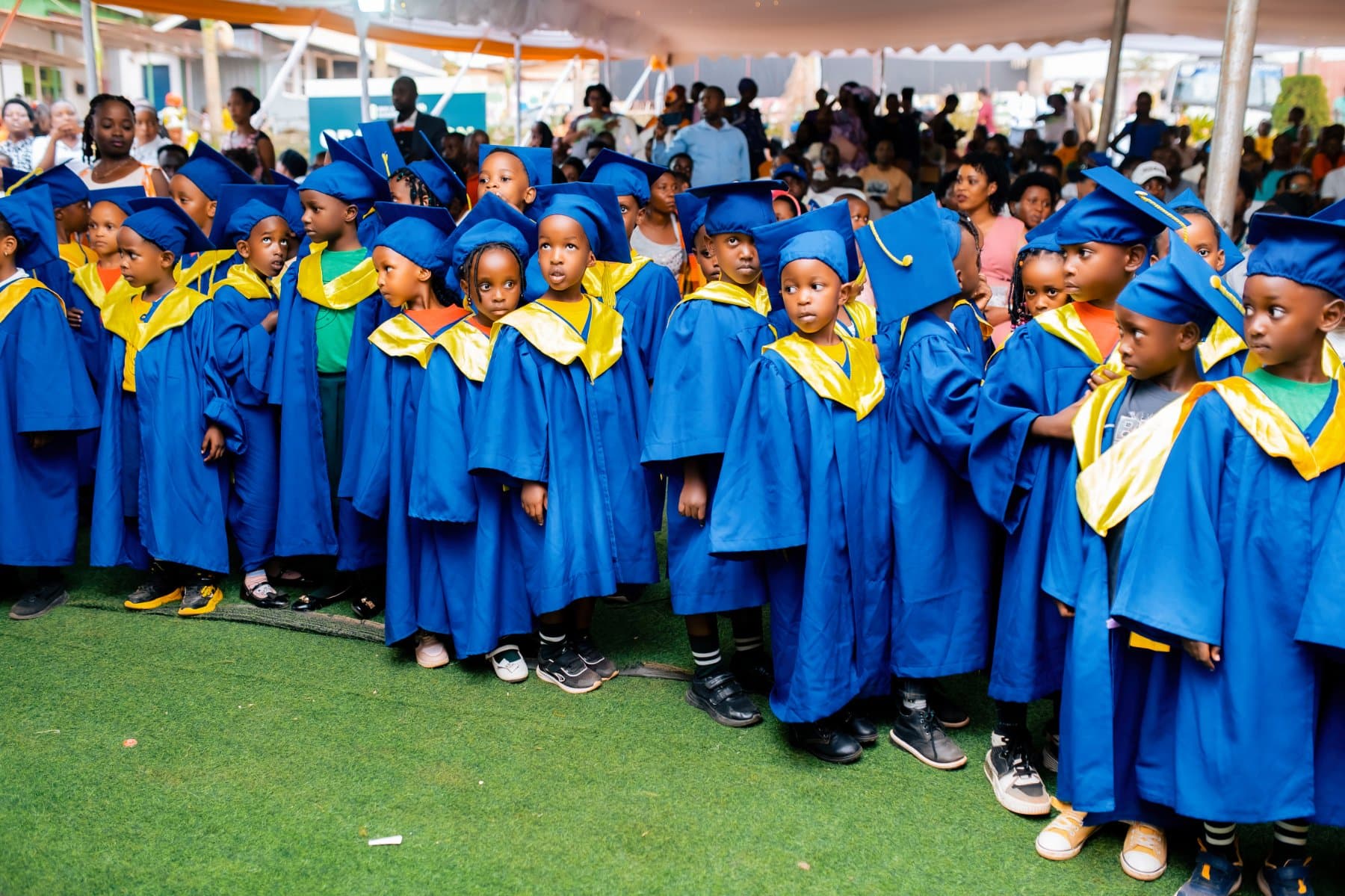 Nursery pupils in blue and gold graduation gowns and caps
