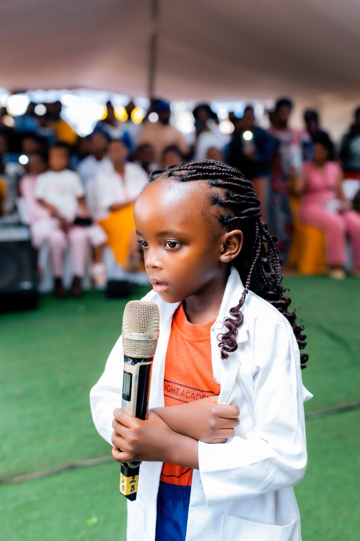 A pupil in a white coat speaking into a microphone