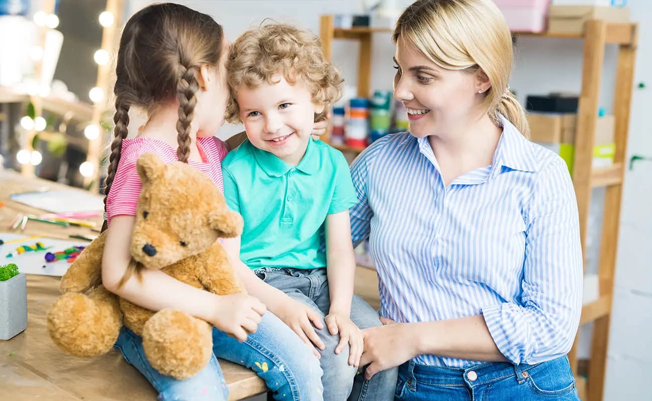 A teacher sitting and talking with two young children